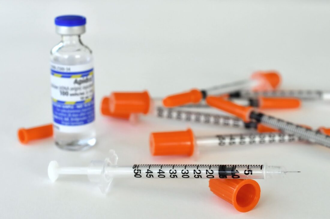 A vial of insulin medicine with a needle or syringe for injections.